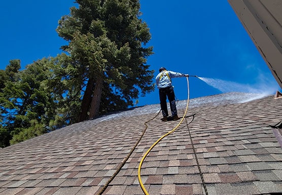 Mills Roofing employee sprays Roof Maxx on commercial building